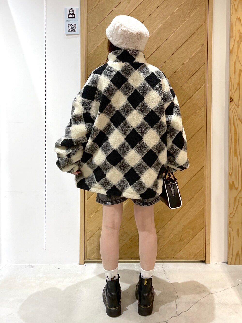 ホワイト系のブルゾン、ブラック系のブーツ、ブラウン系のデニムパンツを着用したレディースの冬コーディネートの3枚目の写真