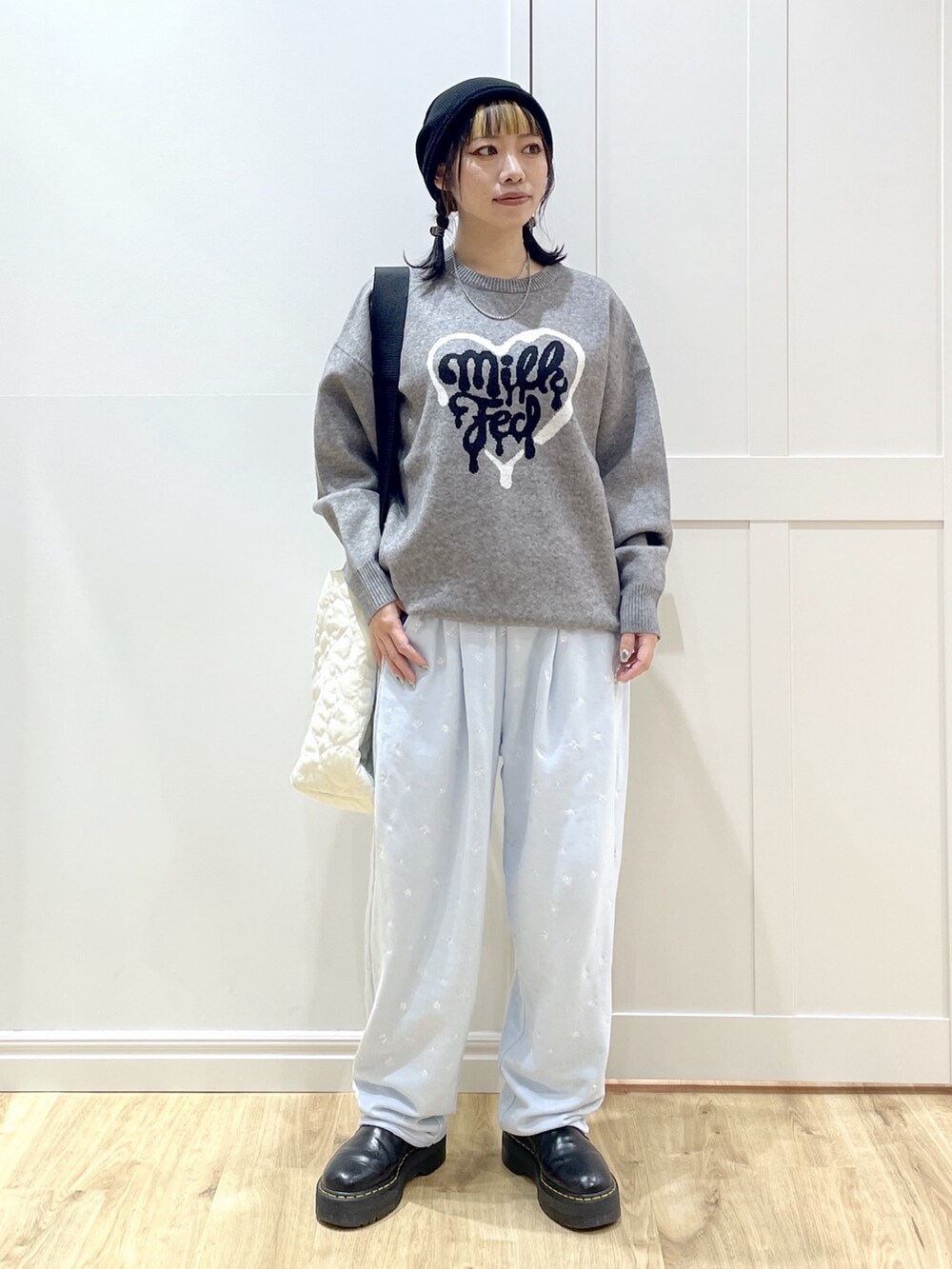 ブルー系のスウェットパンツ、グレー系のニット/セーター、ホワイト系のショルダーバッグを着用したレディースの秋コーディネートの2枚目の写真