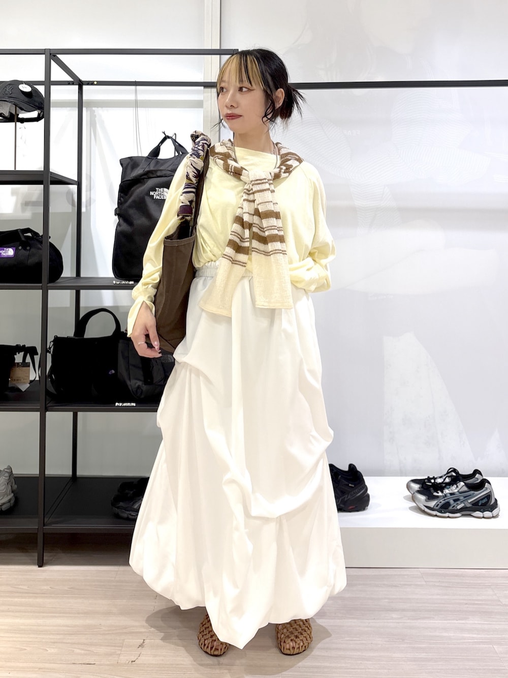 ブラウン系のトートバッグ、イエロー系のTシャツ/カットソー、ホワイト系のカーディガン/ボレロを着用したレディースの春コーディネートの2枚目の写真