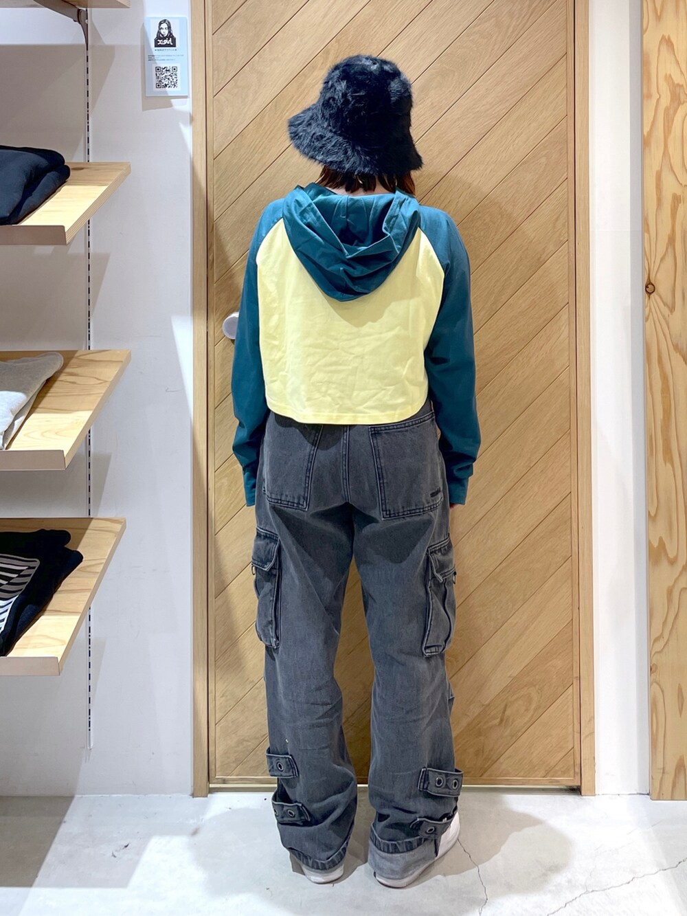 グリーン系のパーカー、ブラック系のカーゴパンツ、ブラック系のハットを着用したレディースの冬コーディネートの2枚目の写真