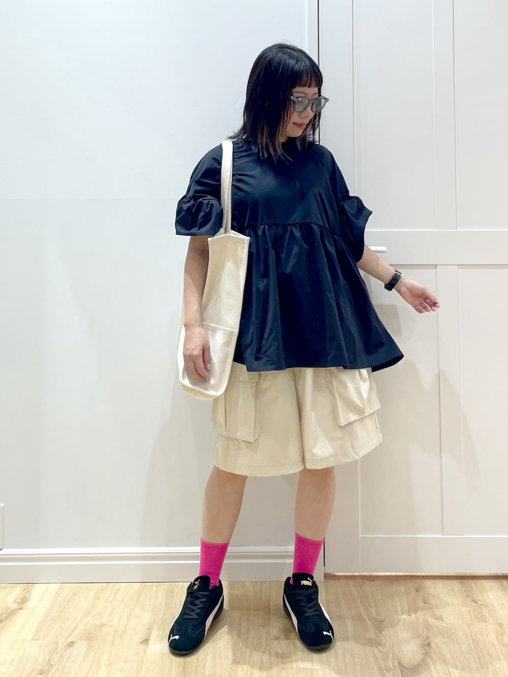 ブラック系のスニーカー、ホワイト系のトートバッグ、ブルー系のサングラスを着用したレディースの夏コーディネートの4枚目の写真