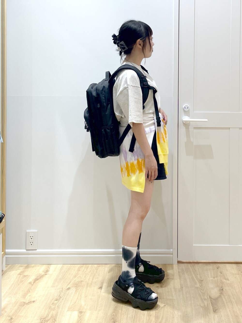 ホワイト系のTシャツ/カットソー、ブラック系のバックパック/リュック、ベージュ系のTシャツ/カットソーを着用したレディースの春コーディネートの2枚目の写真