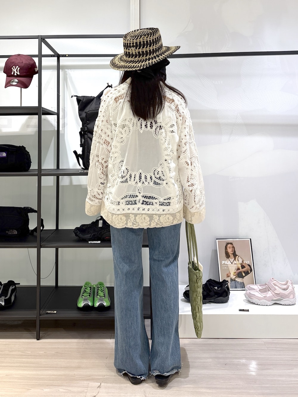 グリーン系のトートバッグ、ブラック系のサンダル、ブルー系のデニムパンツを着用したレディースの春コーディネートの3枚目の写真