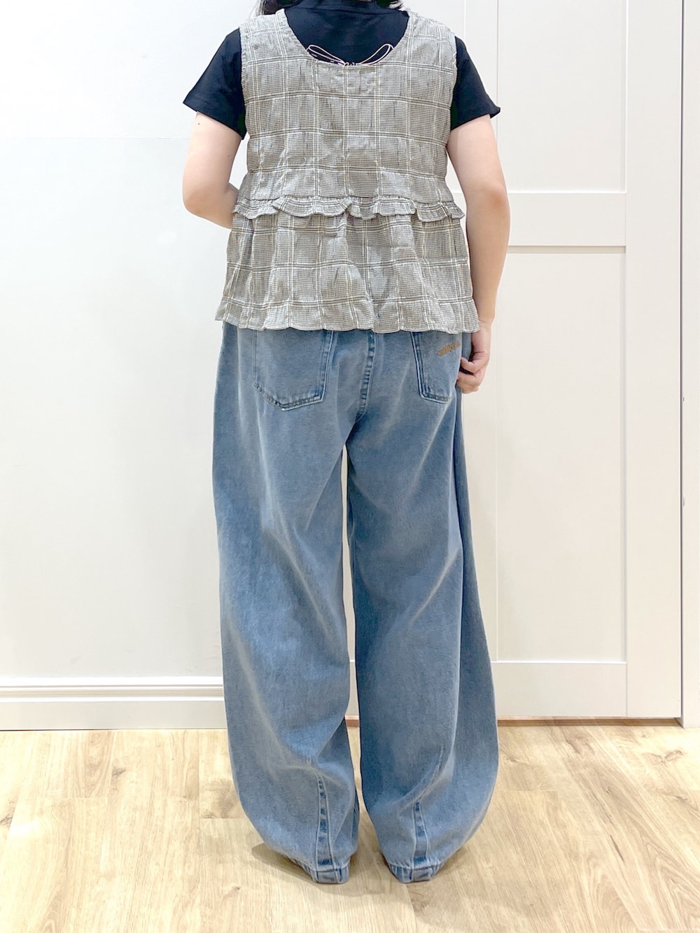 ブルー系のデニムパンツ、ブラック系のショルダーバッグ、ブラック系のタンクトップを着用したレディースの春コーディネートの3枚目の写真