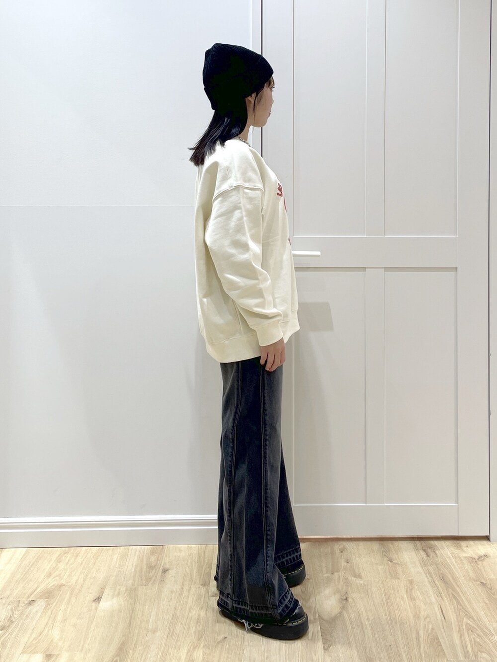 ブラック系のデニムパンツ、レッド系のワンピース、ホワイト系のスウェットを着用したレディースの秋コーディネートの6枚目の写真