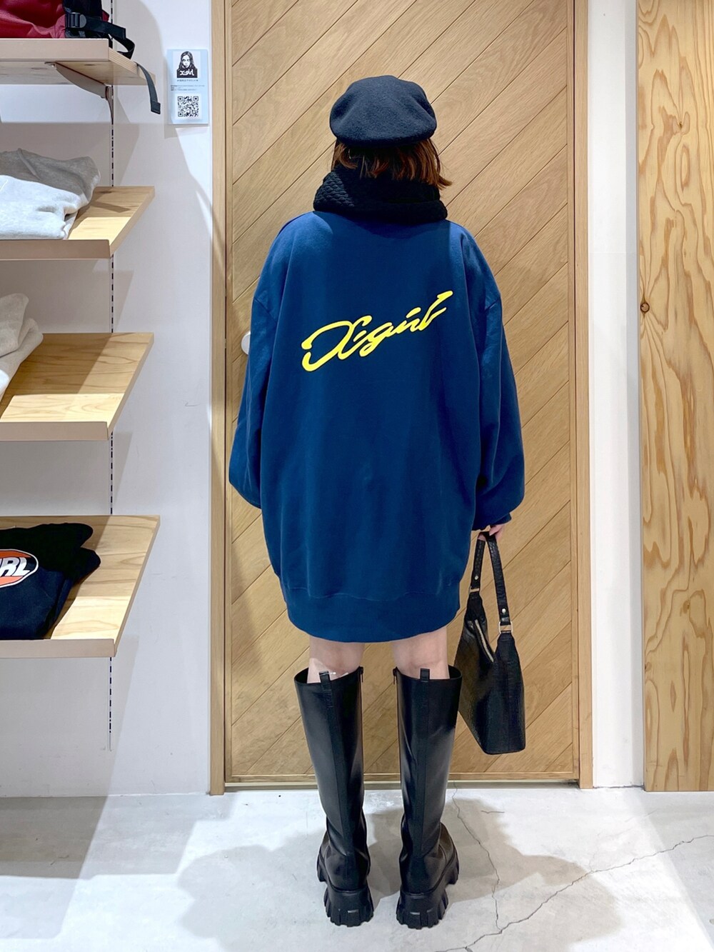 ブルー系のスウェット、ブラック系のブーツ、ブラック系のハンドバッグを着用したレディースの秋コーディネートの2枚目の写真