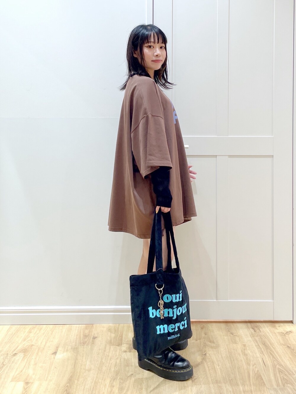 ブラウン系のTシャツ/カットソー、ブラック系のトートバッグ、ブラック系のブーツを着用したレディースの夏コーディネートの2枚目の写真