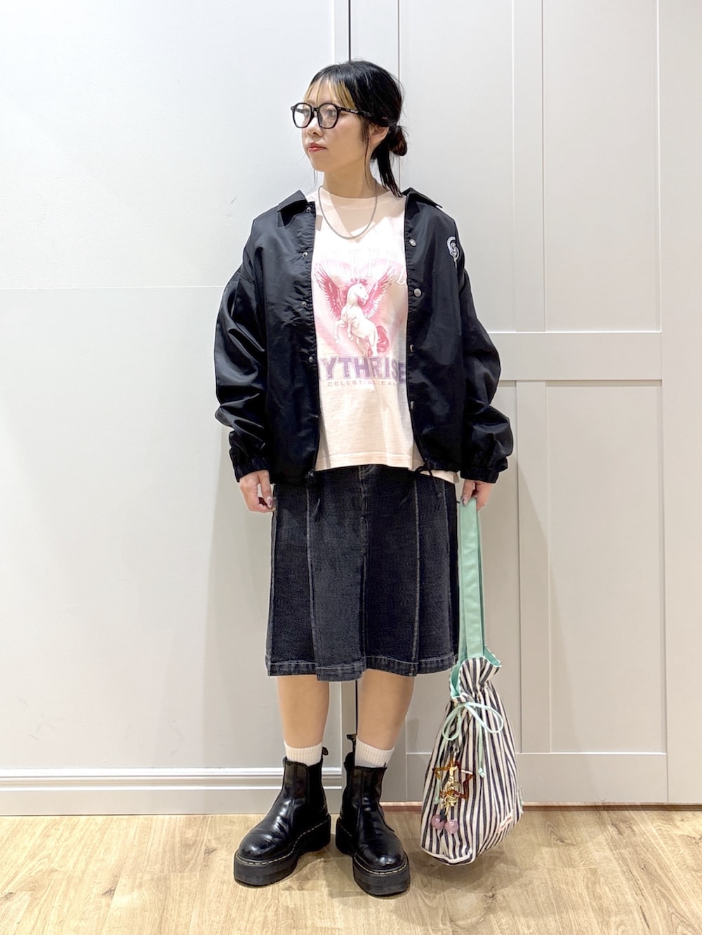 ブラック系のブルゾン、ピンク系のTシャツ/カットソー、ブラック系のデニムスカートを着用したレディースの春コーディネートの3枚目の写真