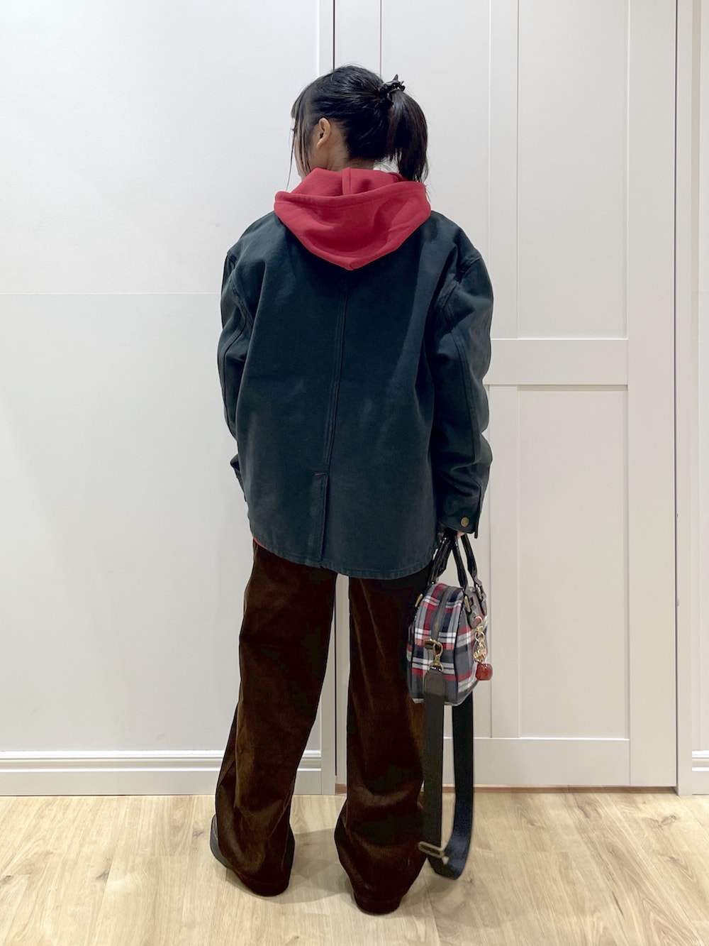 ブラック系のTシャツ/カットソー、レッド系のパーカー、ブラック系のブルゾンを着用したレディースの秋コーディネートの3枚目の写真