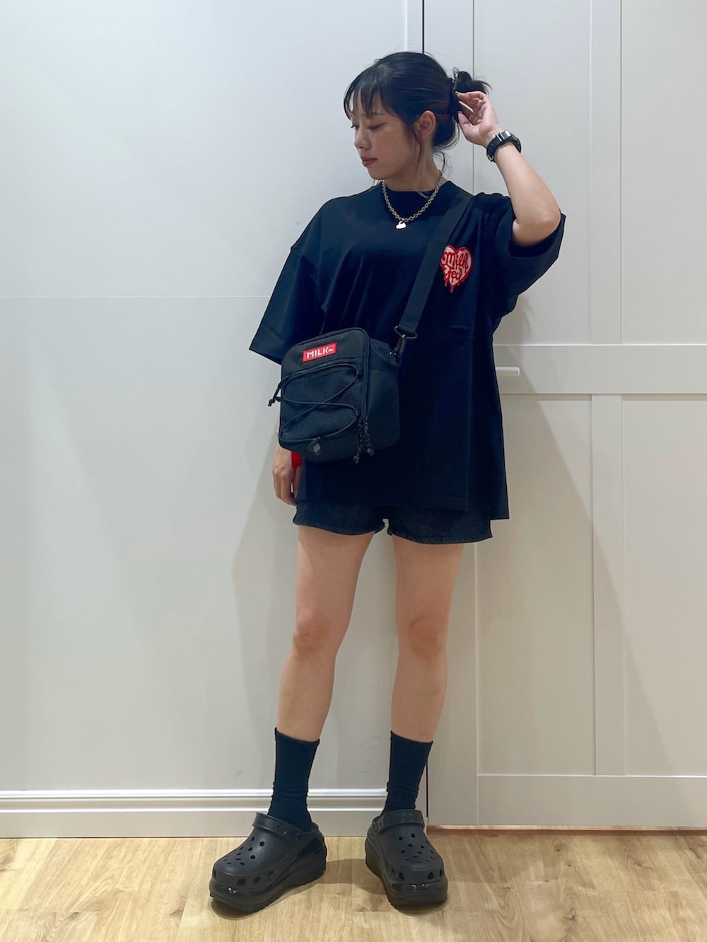 レッド系のショルダーバッグ、ブラック系のデニムパンツ、ブラック系のTシャツ/カットソーを着用したレディースの夏コーディネートの3枚目の写真