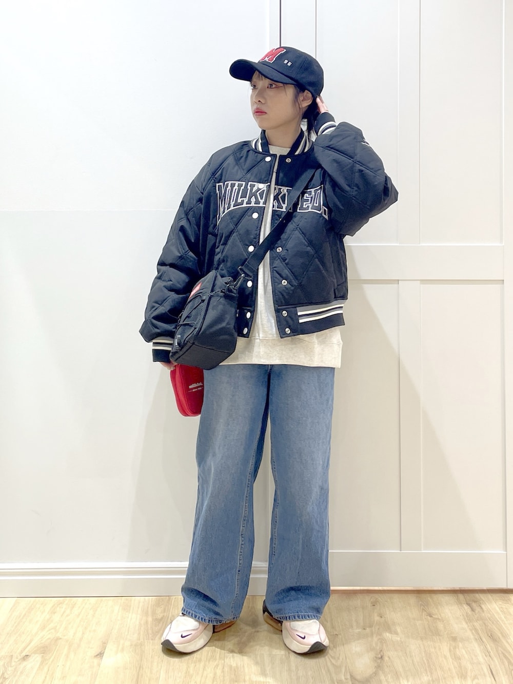 ブルー系のデニムパンツ、ベージュ系のスウェット、レッド系のショルダーバッグを着用したレディースの冬コーディネートの3枚目の写真