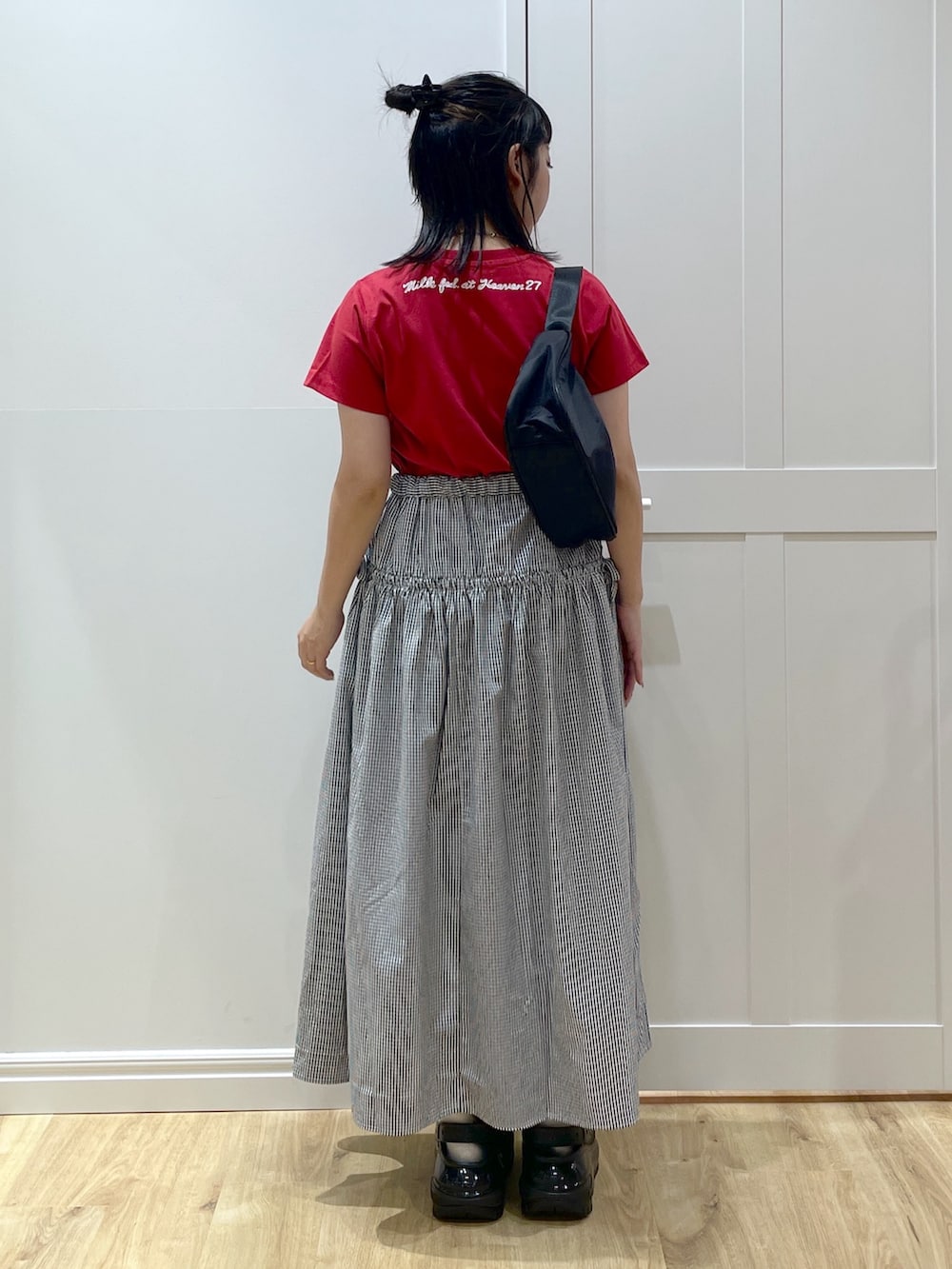 ブラック系のスカート、ブラック系のハンドバッグ、レッド系のTシャツ/カットソーを着用したレディースの夏コーディネートの3枚目の写真