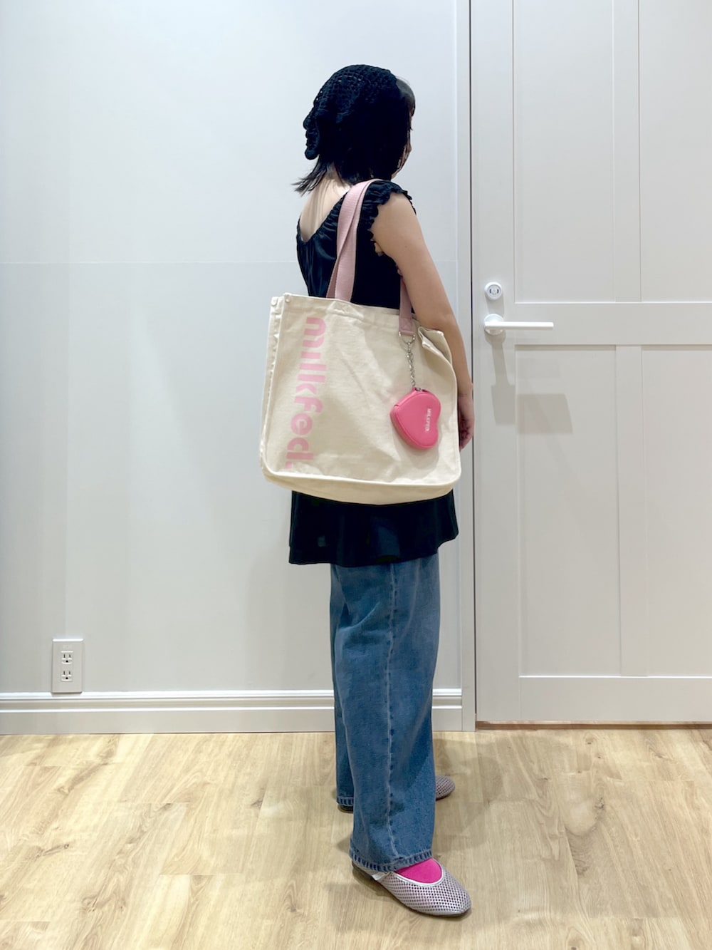ホワイト系のトートバッグ、ブラック系のワンピース、ブルー系のデニムパンツを着用したレディースの夏コーディネートの2枚目の写真