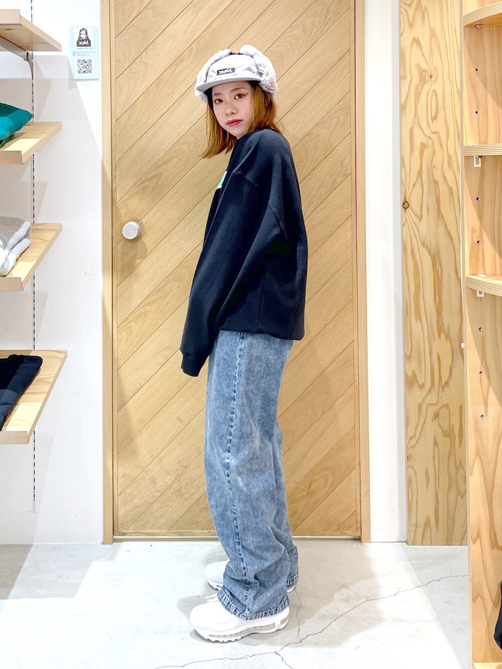 ブルー系のデニムパンツ、ブルー系のスウェット、ホワイト系のスニーカーを着用したレディースの秋コーディネートの3枚目の写真