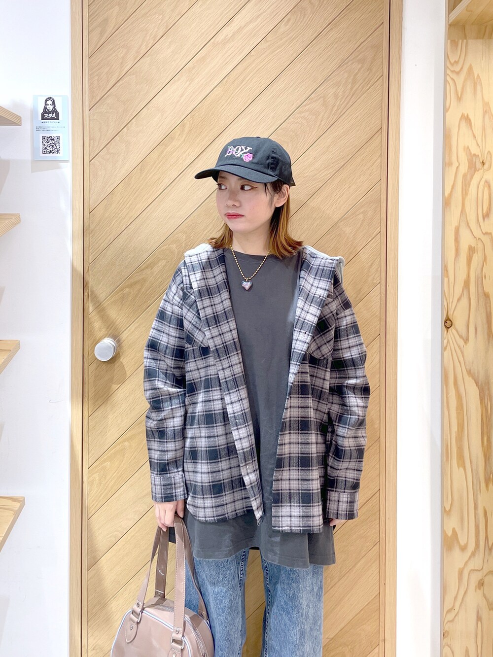 ベージュ系のボストンバッグ、ブルー系のデニムパンツ、ブラック系のスニーカーを着用したレディースの秋コーディネートの2枚目の写真