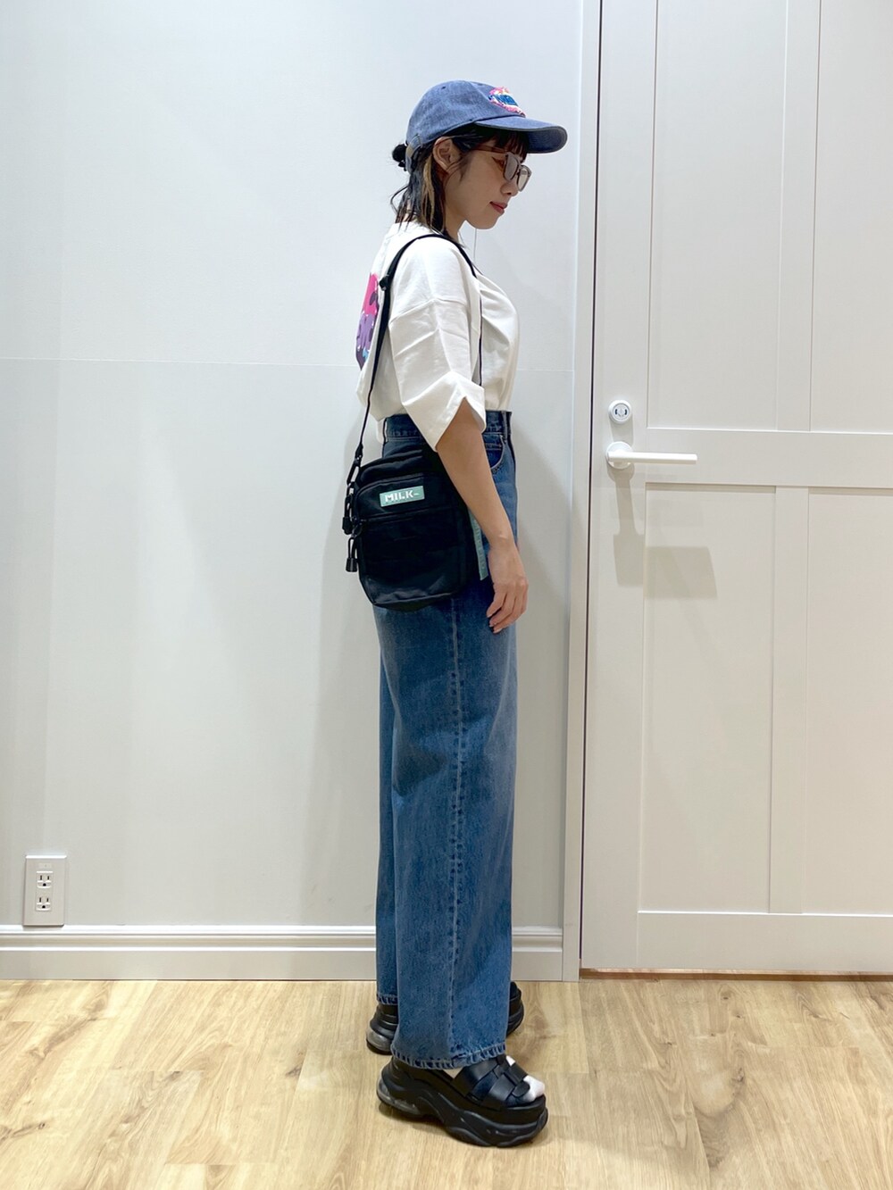 グリーン系のショルダーバッグ、ブラック系のサンダル、ホワイト系のTシャツ/カットソーを着用したレディースの夏コーディネートの3枚目の写真