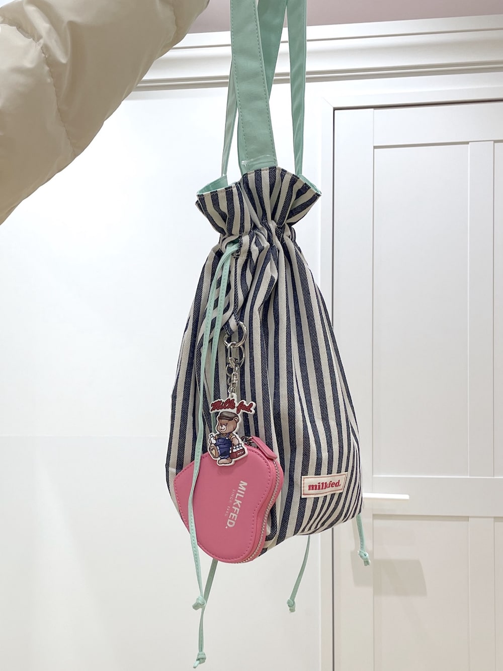 ホワイト系のダウンジャケット/コート、ベージュ系のTシャツ/カットソー、ブルー系のデニムパンツを着用したレディースの冬コーディネートの8枚目の写真