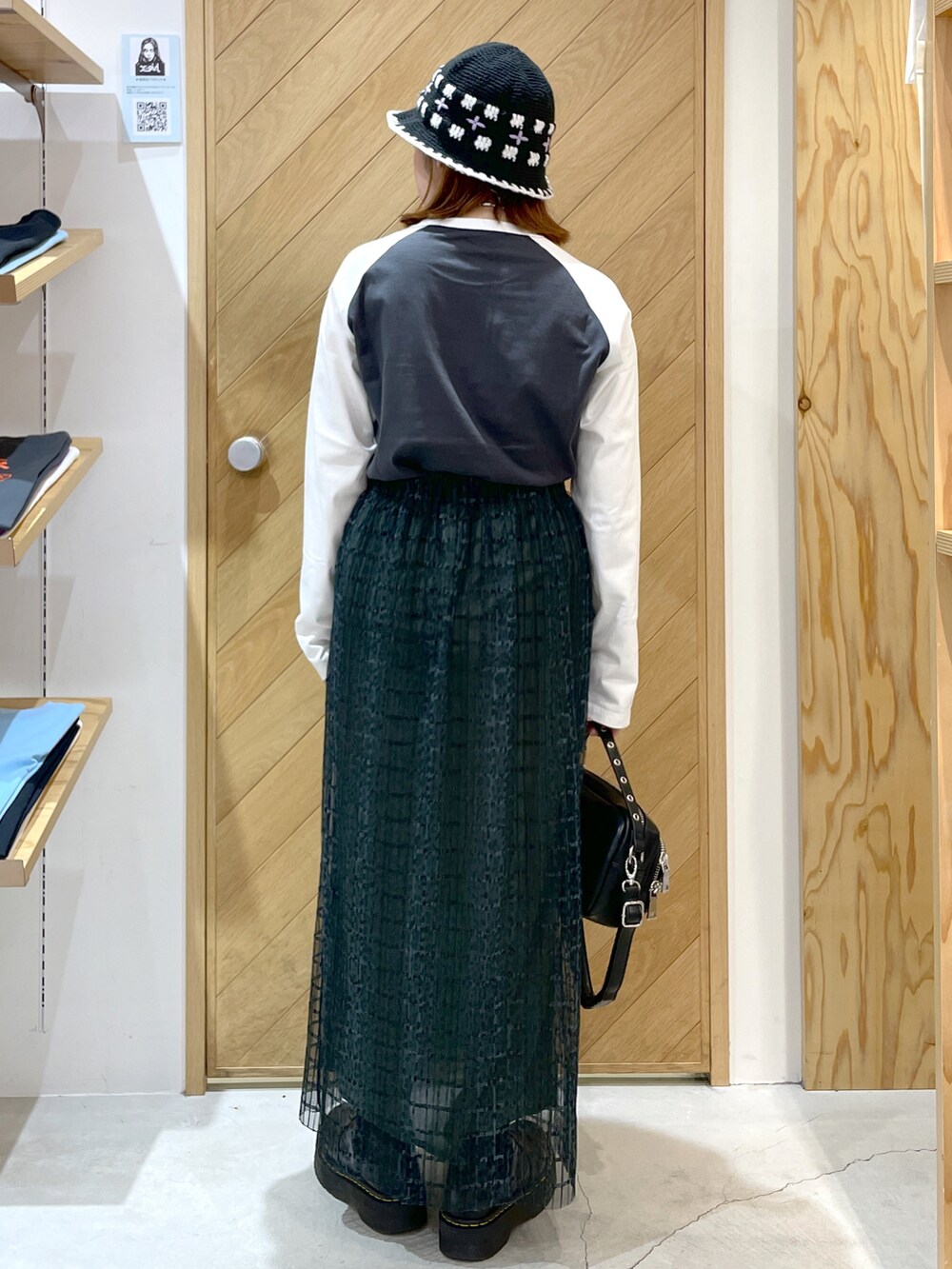 ブラック系のショルダーバッグ、グリーン系のスカート、ブラック系のブーツを着用したレディースの秋コーディネートの3枚目の写真