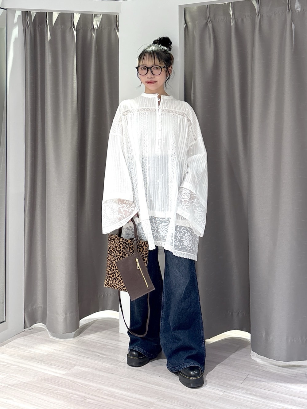 ホワイト系のシャツ/ブラウス、ブルー系のデニムパンツ、ブラック系のブーツを着用したレディースの秋コーディネートの2枚目の写真