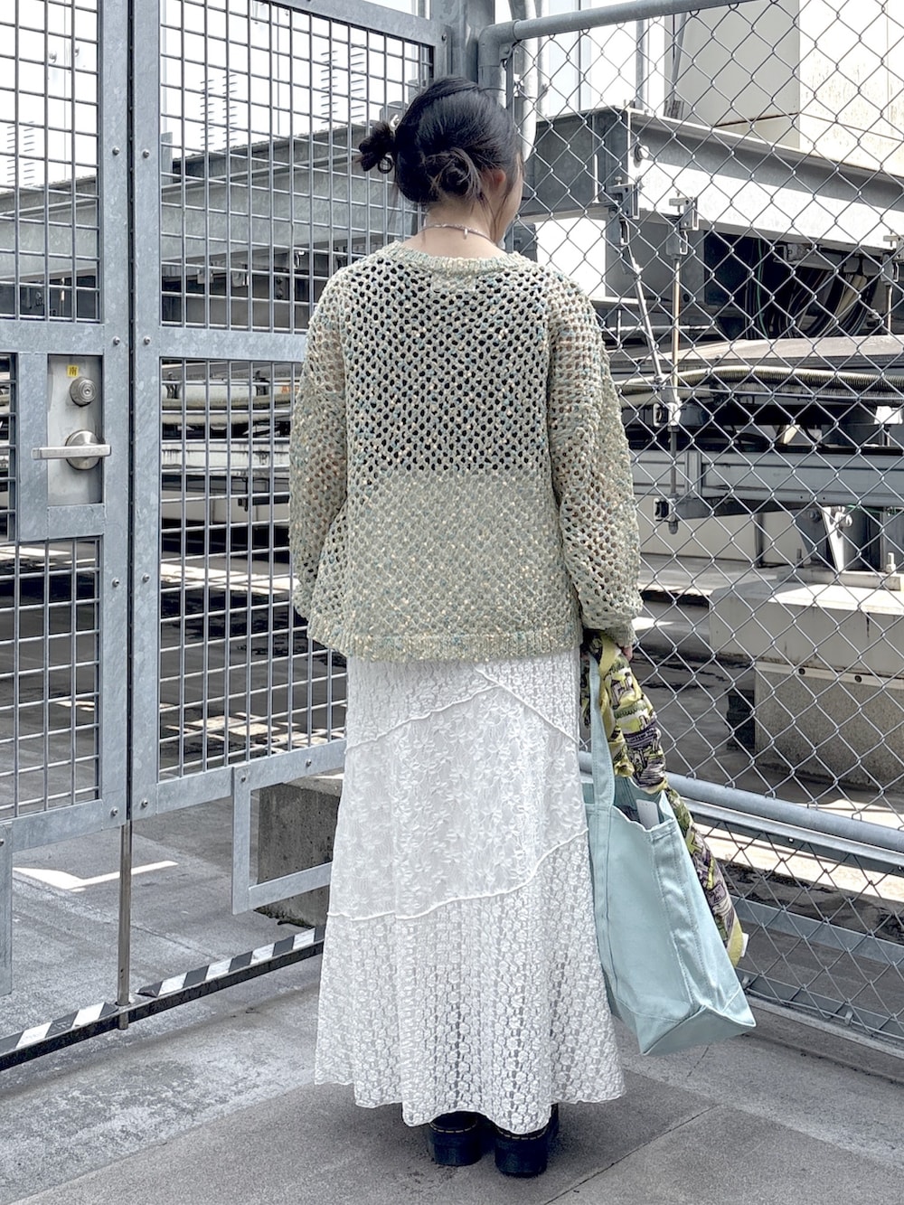 ブラック系のブーツ、ブルー系のニット/セーター、ホワイト系のスカートを着用したレディースの春コーディネートの3枚目の写真