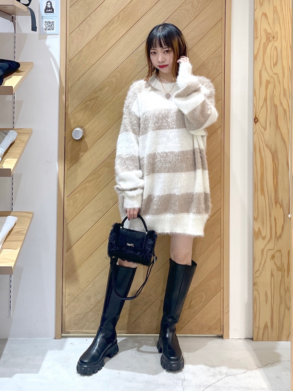 ブラック系のショルダーバッグ、ブラック系のブーツ、ホワイト系のニット/セーターを着用したレディースの冬コーディネートの2枚目の写真