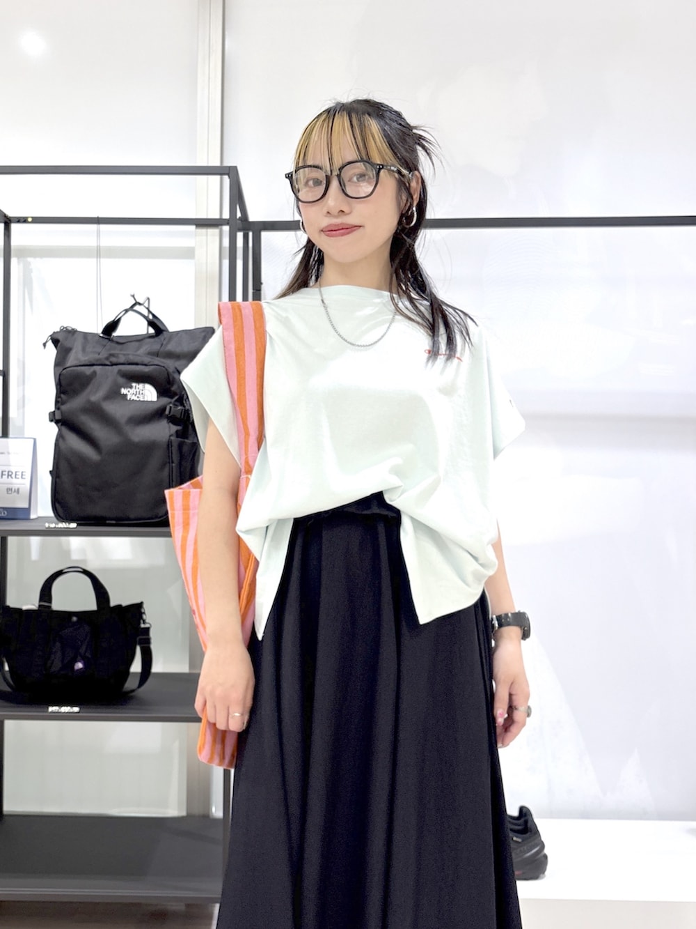 ブルー系のスカート、グリーン系のTシャツ/カットソー、シルバー系のスニーカーを着用したレディースの春コーディネートの6枚目の写真