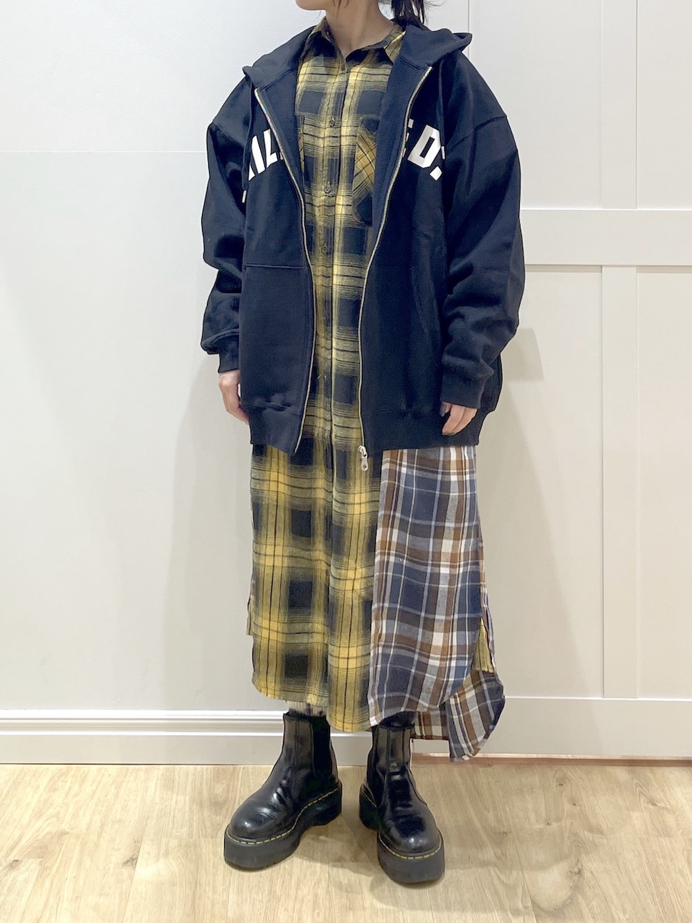 ブラウン系のベスト、イエロー系のワンピース、ブラック系のブーツを着用したレディースの冬コーディネートの6枚目の写真