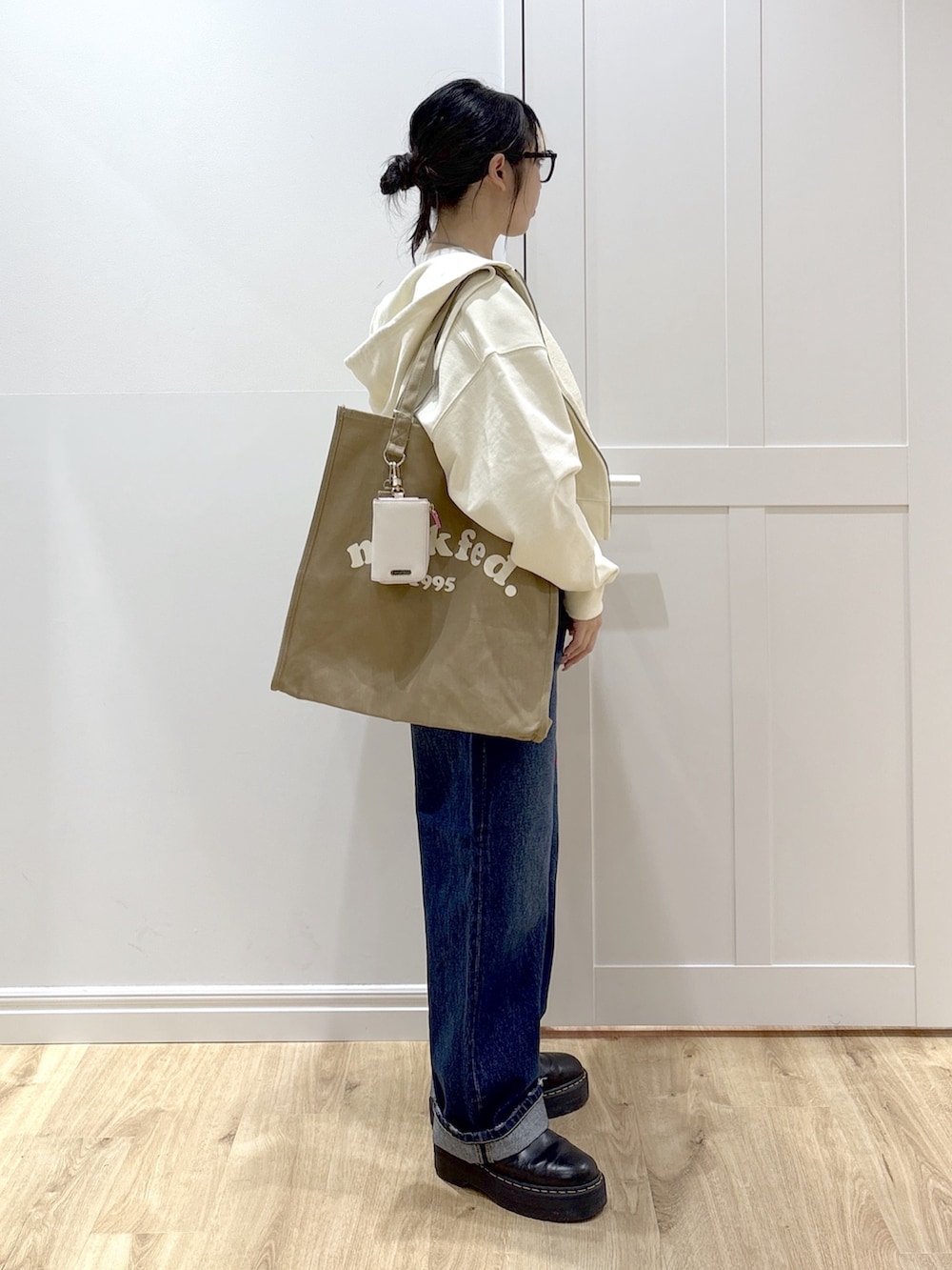 ブラック系のブーツ、ブルー系のデニムパンツ、ホワイト系のパーカーを着用したレディースの春コーディネートの3枚目の写真