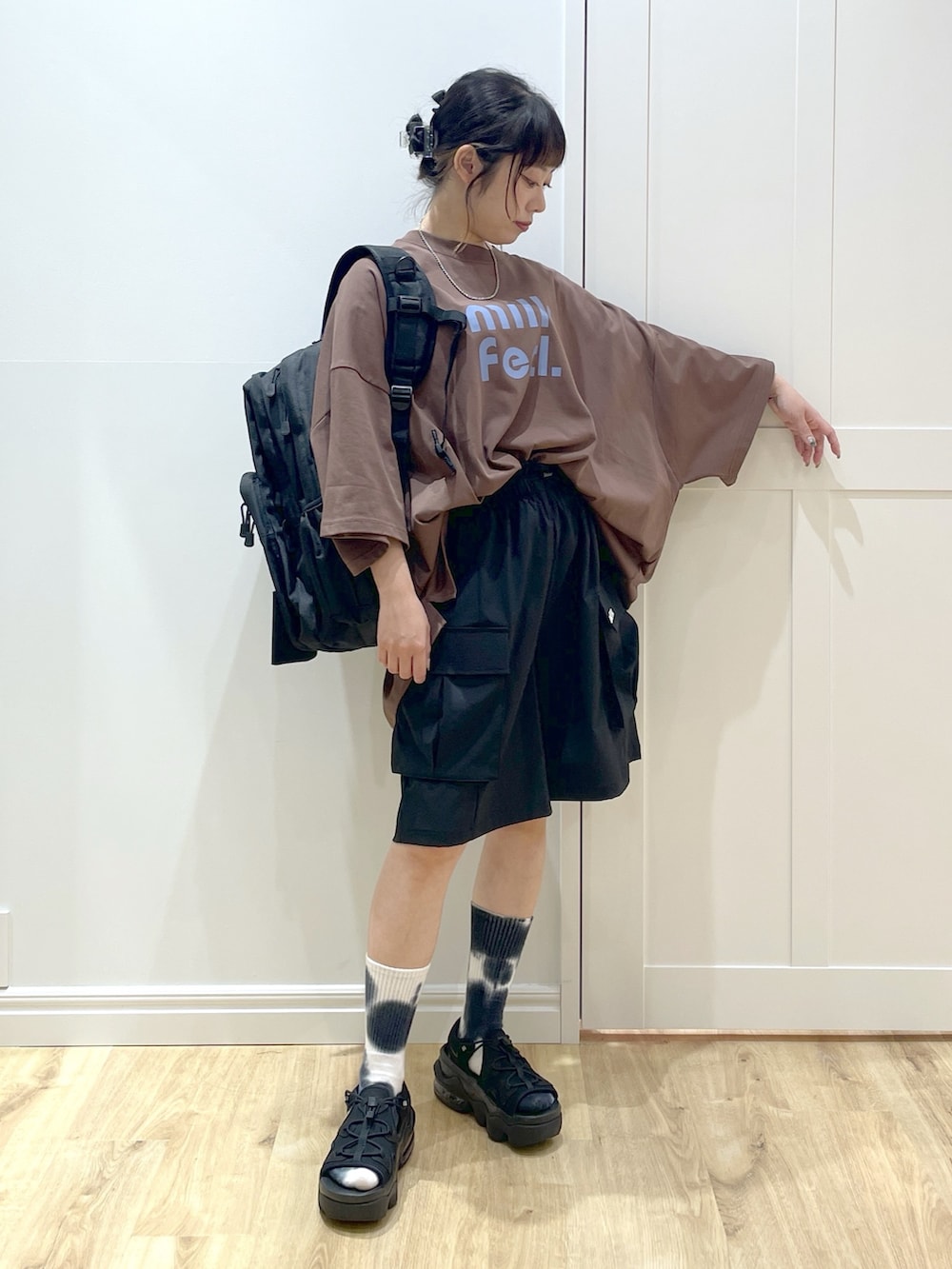 ブラック系のバックパック/リュック、ブラウン系のTシャツ/カットソー、ブラック系のサンダルを着用したレディースの春コーディネートの2枚目の写真