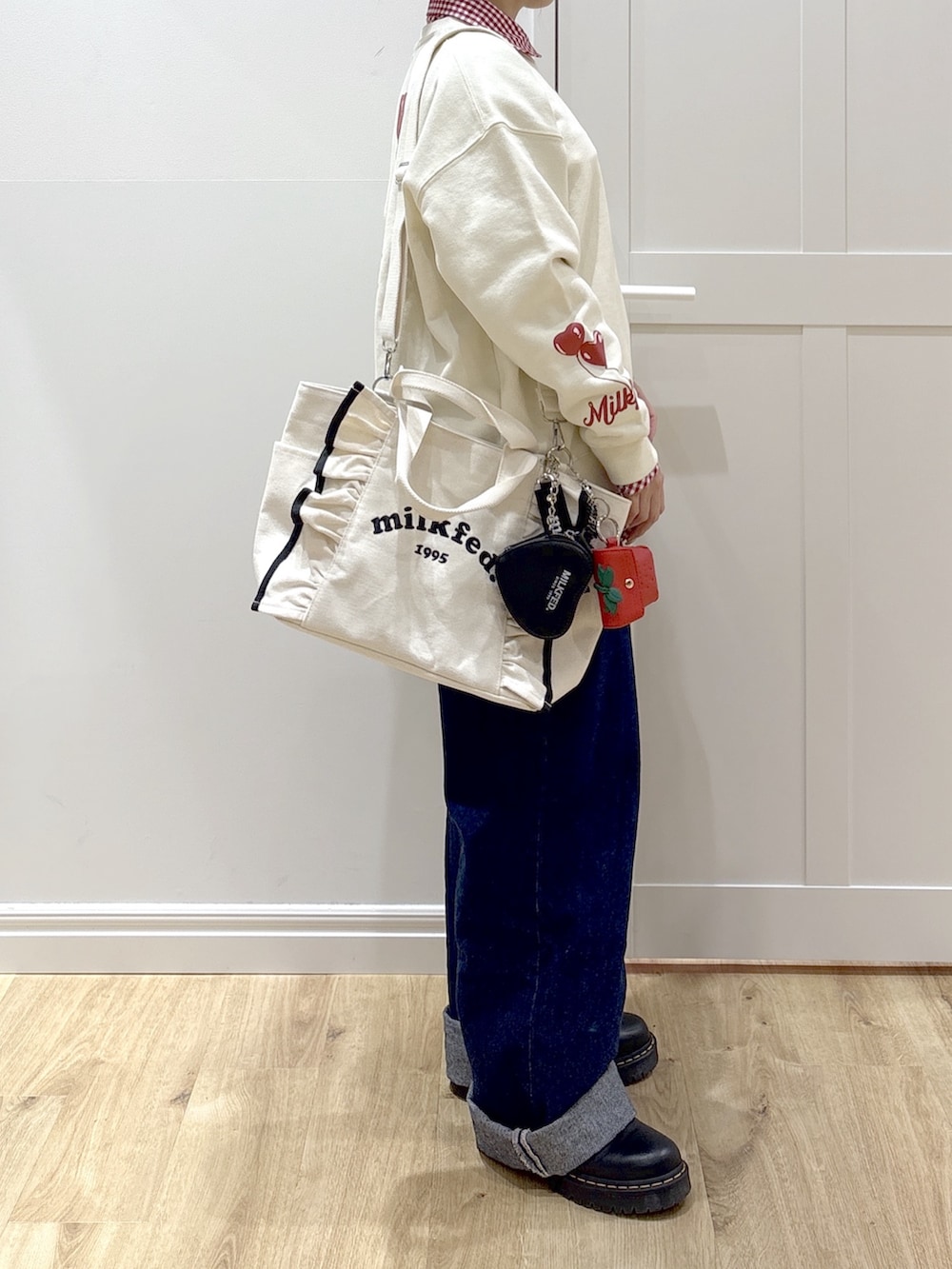 ブルー系のデニムパンツ、レッド系のシャツ/ブラウス、ホワイト系のショルダーバッグを着用したレディースの冬コーディネートの3枚目の写真