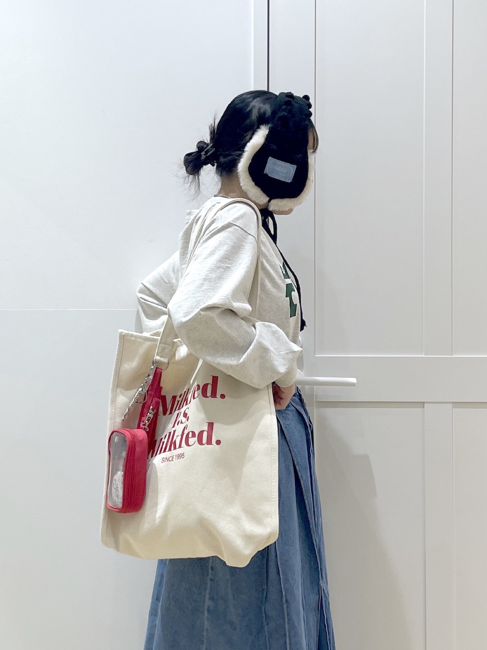 ブルー系のデニムスカート、ベージュ系のTシャツ/カットソー、レッド系のトートバッグを着用したレディースの冬コーディネートの4枚目の写真