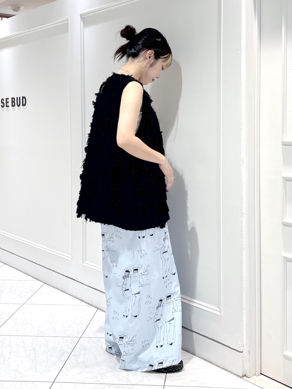 ブルー系のスカート、ブラック系のスニーカー、ブラック系のベストを着用したレディースの夏コーディネートの4枚目の写真
