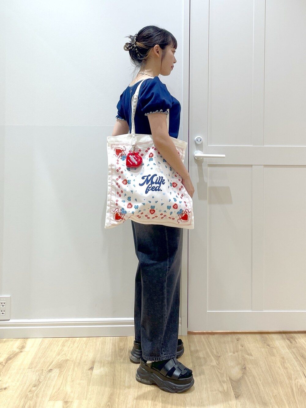 ブルー系のニット/セーター、ブラック系のデニムパンツ、ブラック系のサンダルを着用したレディースの夏コーディネートの2枚目の写真