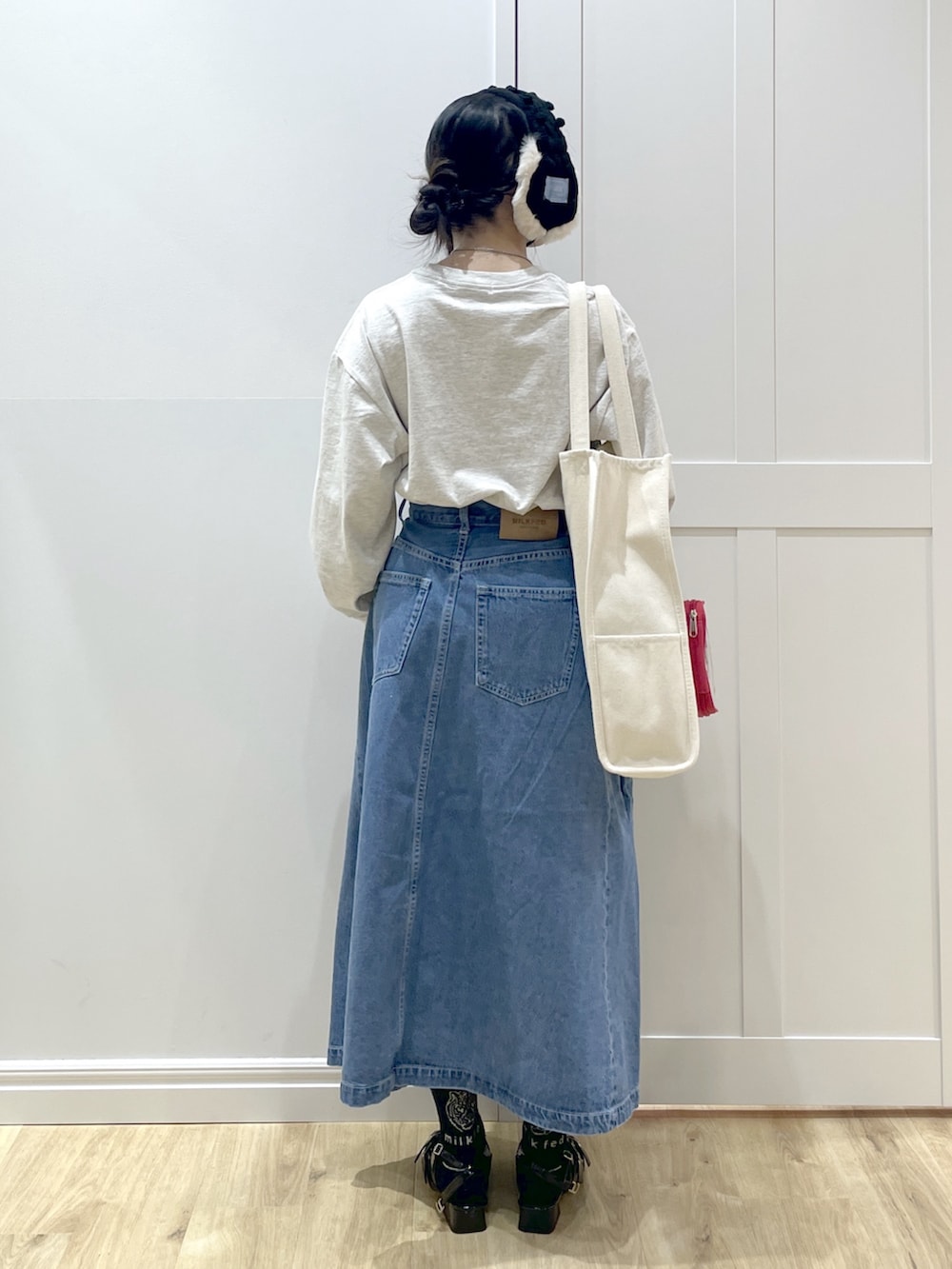 ブルー系のデニムスカート、ベージュ系のTシャツ/カットソー、レッド系のトートバッグを着用したレディースの冬コーディネートの3枚目の写真