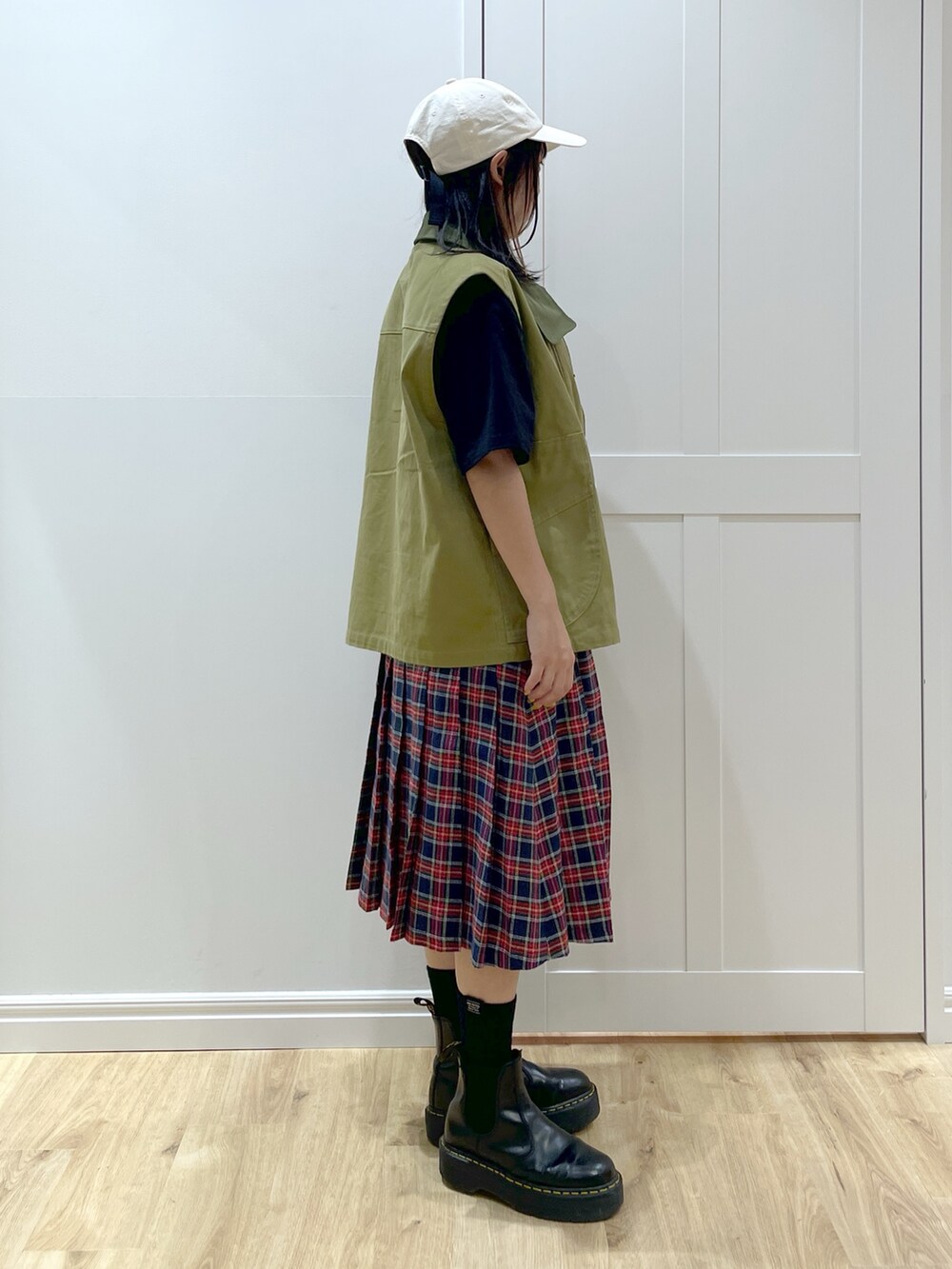 ブラック系のブーツ、ブルー系のスカート、グリーン系のベストを着用したレディースの秋コーディネートの4枚目の写真