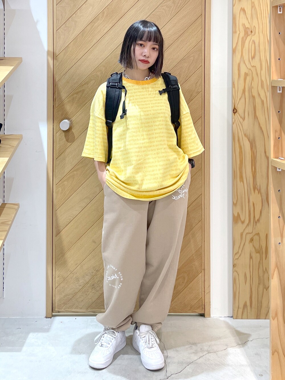 ブラック系のバックパック/リュック、イエロー系のTシャツ/カットソー、ベージュ系のスウェットパンツを着用したレディースの春コーディネートの2枚目の写真