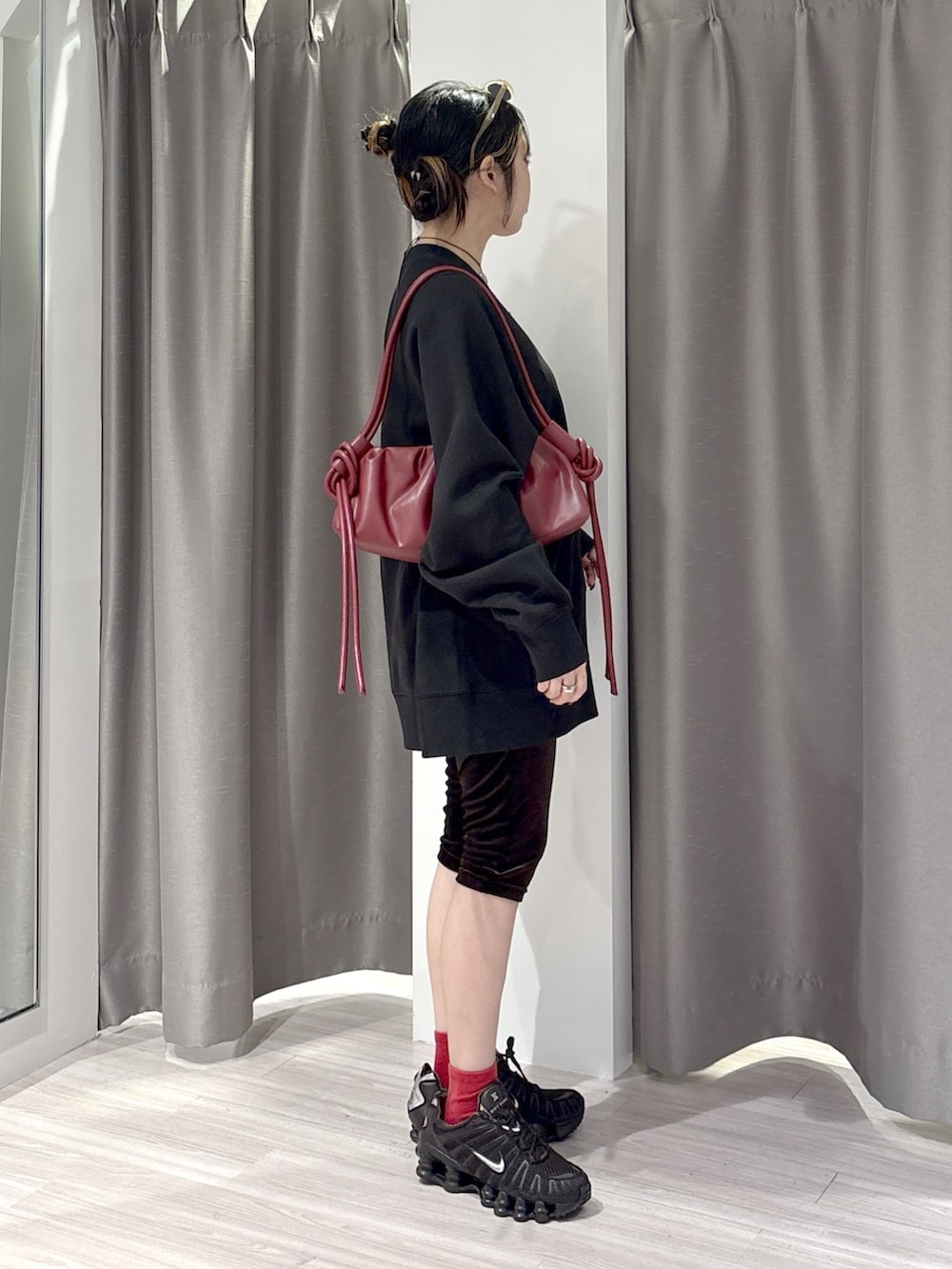ブラック系のスウェット、ブラウン系のその他パンツ、レッド系のハンドバッグを着用したレディースの秋コーディネートの2枚目の写真