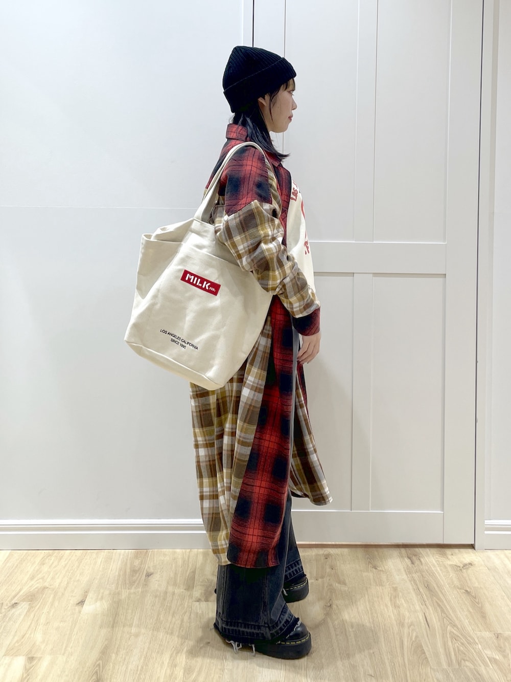 ブラック系のデニムパンツ、レッド系のワンピース、ホワイト系のスウェットを着用したレディースの秋コーディネートの3枚目の写真