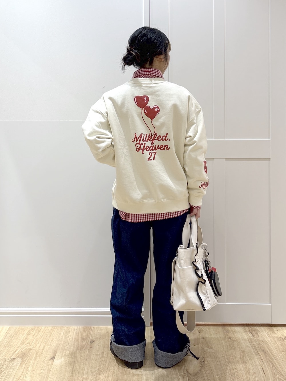 ブルー系のデニムパンツ、レッド系のシャツ/ブラウス、ホワイト系のショルダーバッグを着用したレディースの冬コーディネートの2枚目の写真