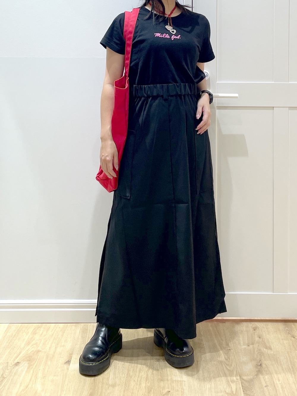 レッド系のトートバッグ、ブラック系のTシャツ/カットソー、ブラック系のスカートを着用したレディースの夏コーディネートの4枚目の写真