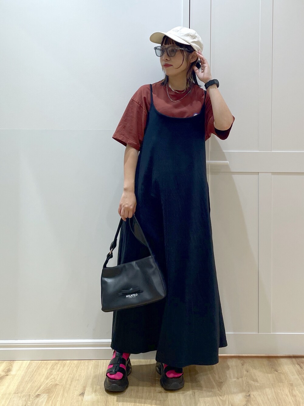 ブラック系のワンピース、ブラウン系のTシャツ/カットソー、ブラック系のサンダルを着用したレディースの夏コーディネートの2枚目の写真