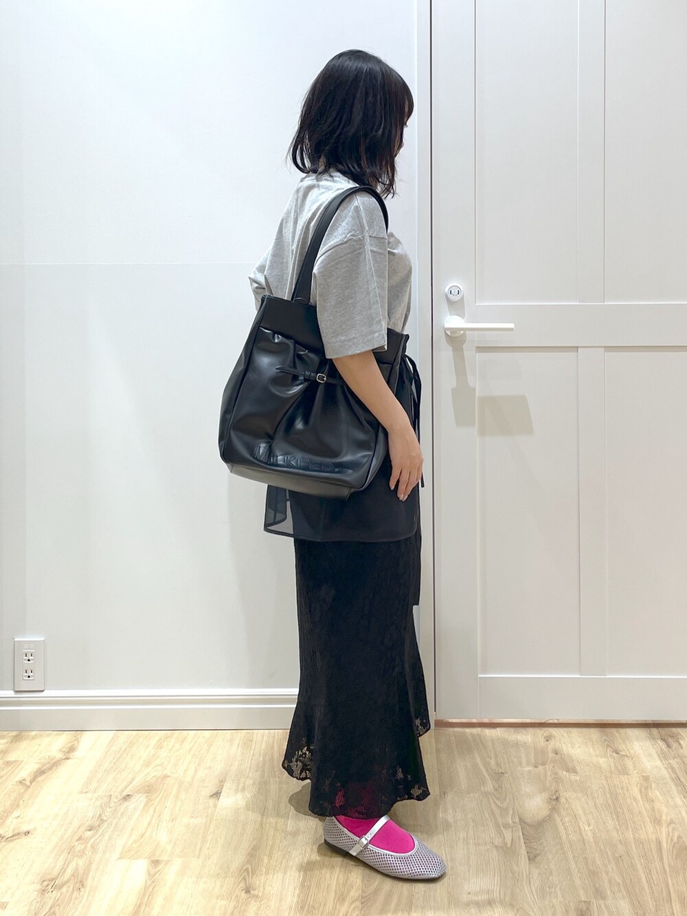 ブラック系のスカート、ブラック系のトートバッグ、グレー系のTシャツ/カットソーを着用したレディースの春コーディネートの2枚目の写真