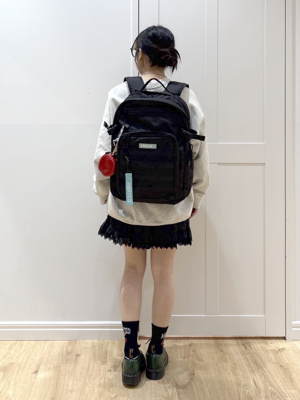 ブラック系のスカート、ベージュ系のスウェット、グリーン系のバックパック/リュックを着用したレディースの春コーディネートの2枚目の写真