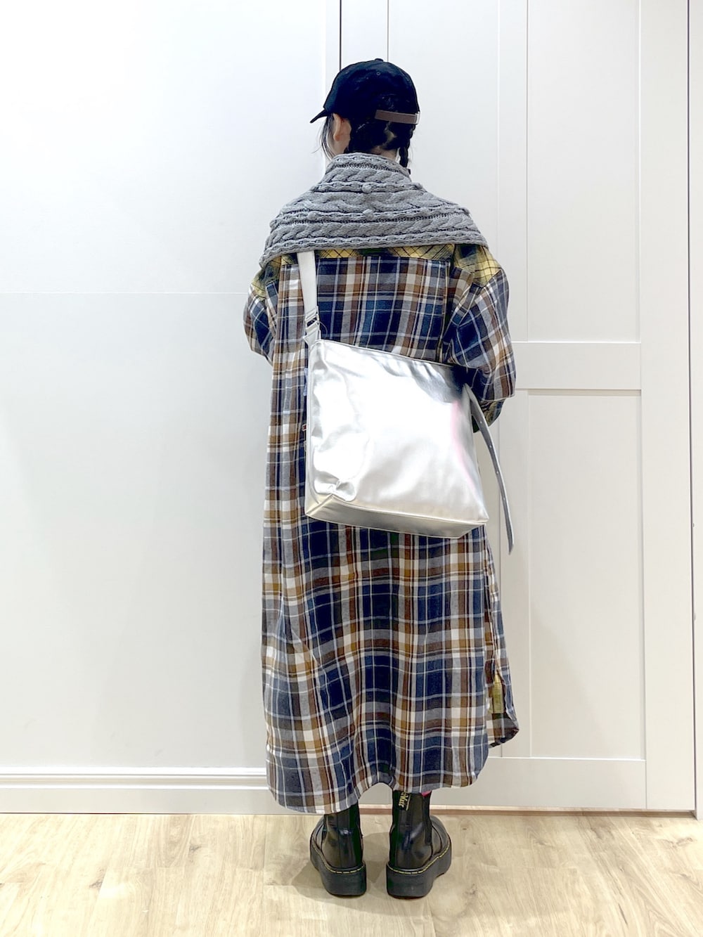 イエロー系のワンピース、ブラック系のブーツ、シルバー系のショルダーバッグを着用したレディースの秋コーディネートの5枚目の写真