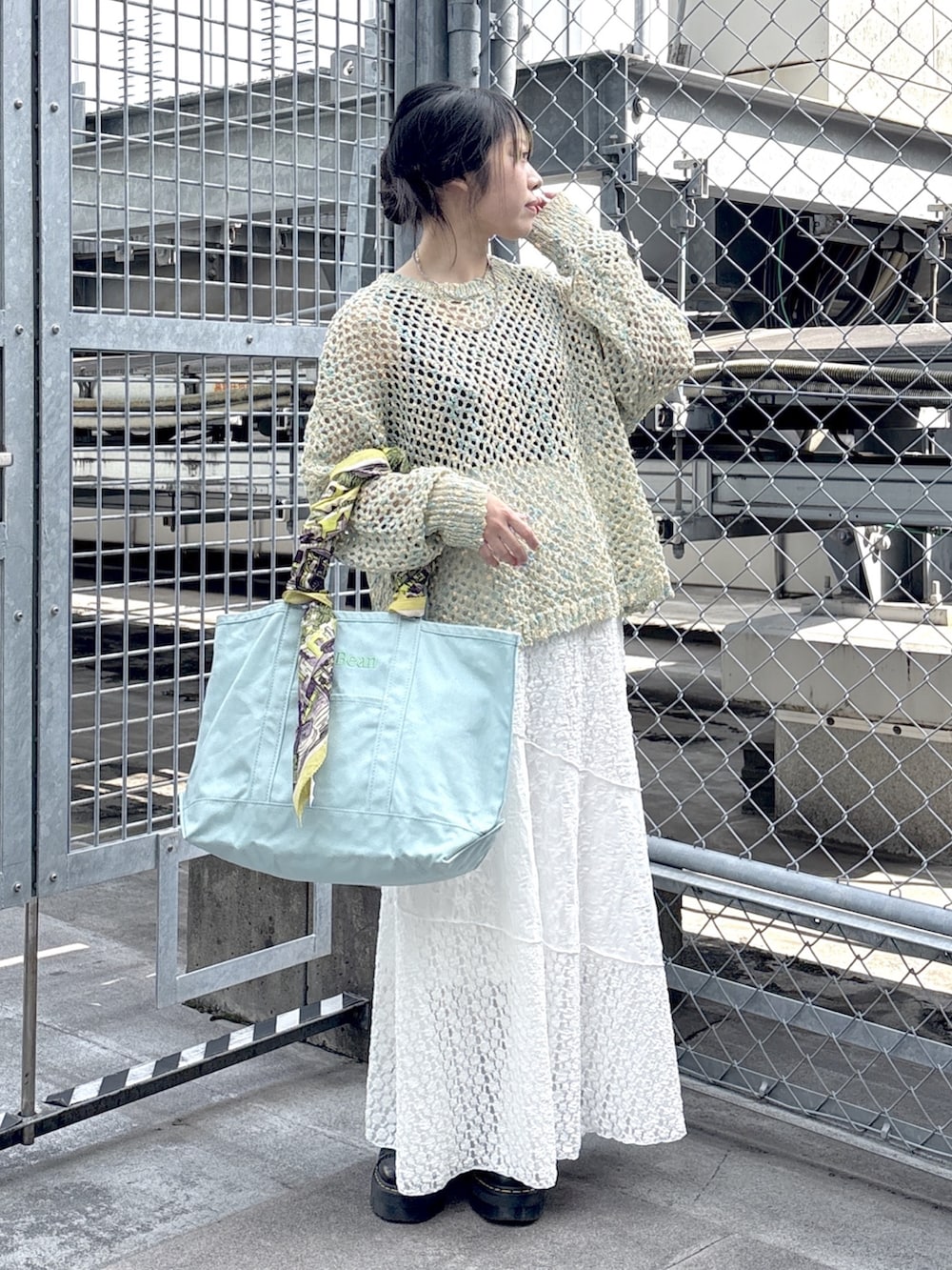 ブラック系のブーツ、ブルー系のニット/セーター、ホワイト系のスカートを着用したレディースの春コーディネートの4枚目の写真