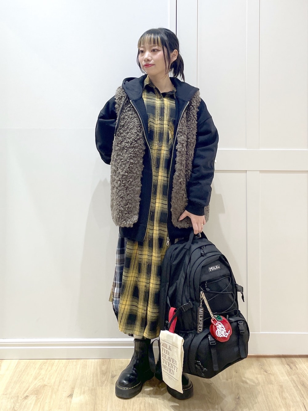 ブラウン系のベスト、イエロー系のワンピース、ブラック系のブーツを着用したレディースの冬コーディネートの3枚目の写真