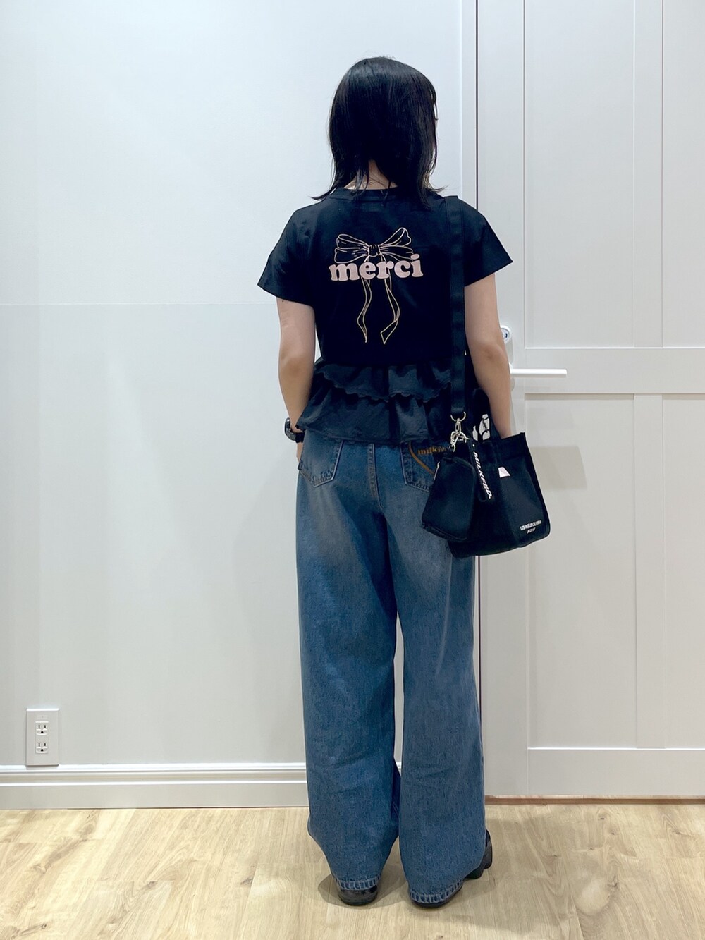 ピンク系のショルダーバッグ、ブルー系のデニムパンツ、ブラック系のサンダルを着用したレディースの夏コーディネートの2枚目の写真