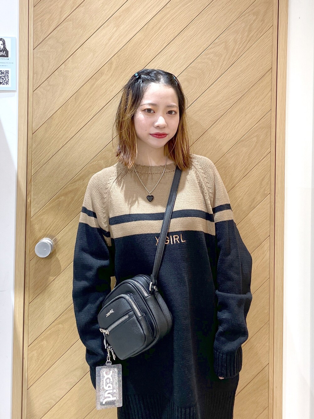 ブラック系のショルダーバッグ、ブラック系のワンピース、ブラック系のブーツを着用したレディースの秋コーディネートの2枚目の写真