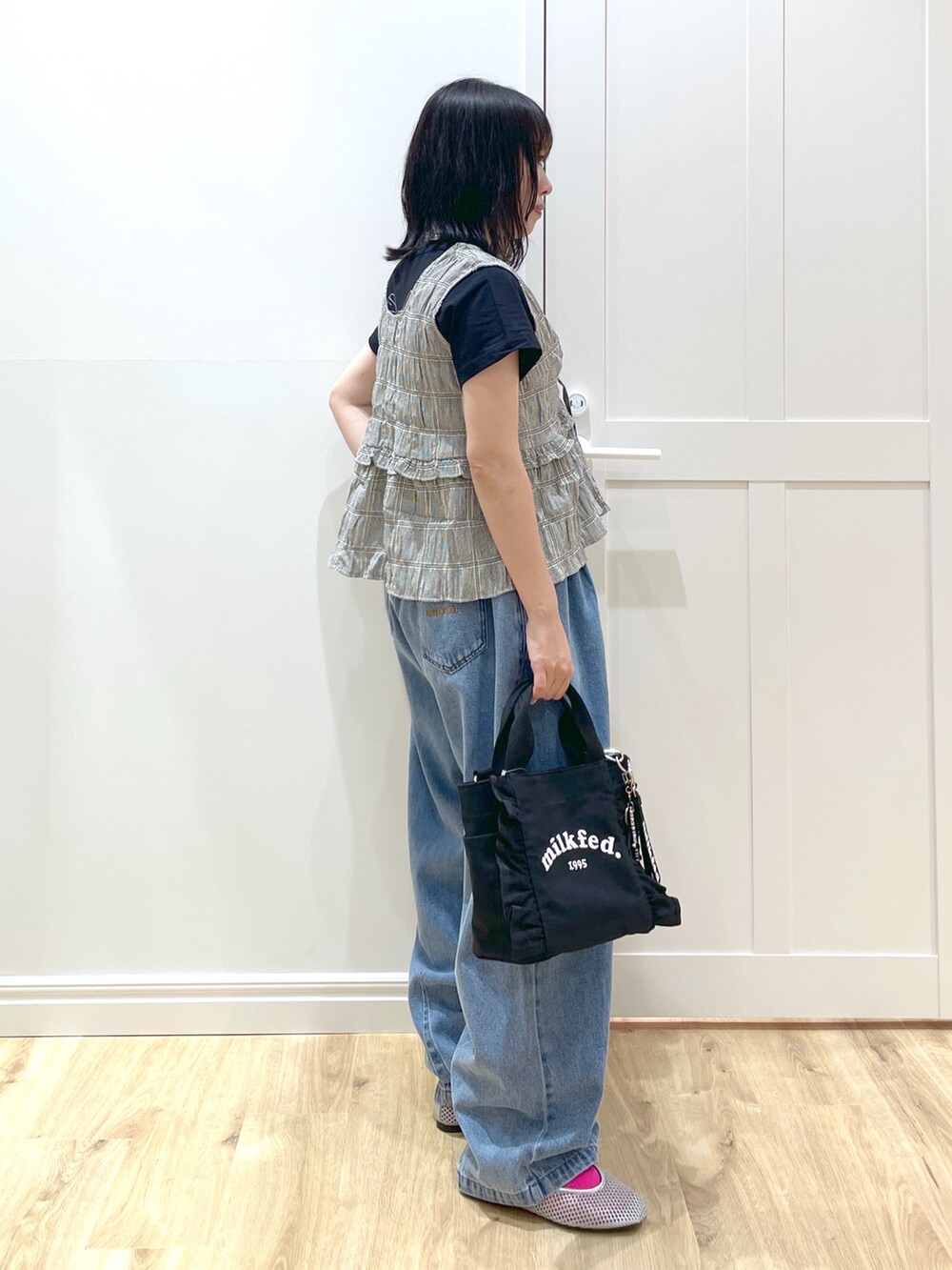 ブルー系のデニムパンツ、ブラック系のショルダーバッグ、ブラック系のタンクトップを着用したレディースの春コーディネートの2枚目の写真