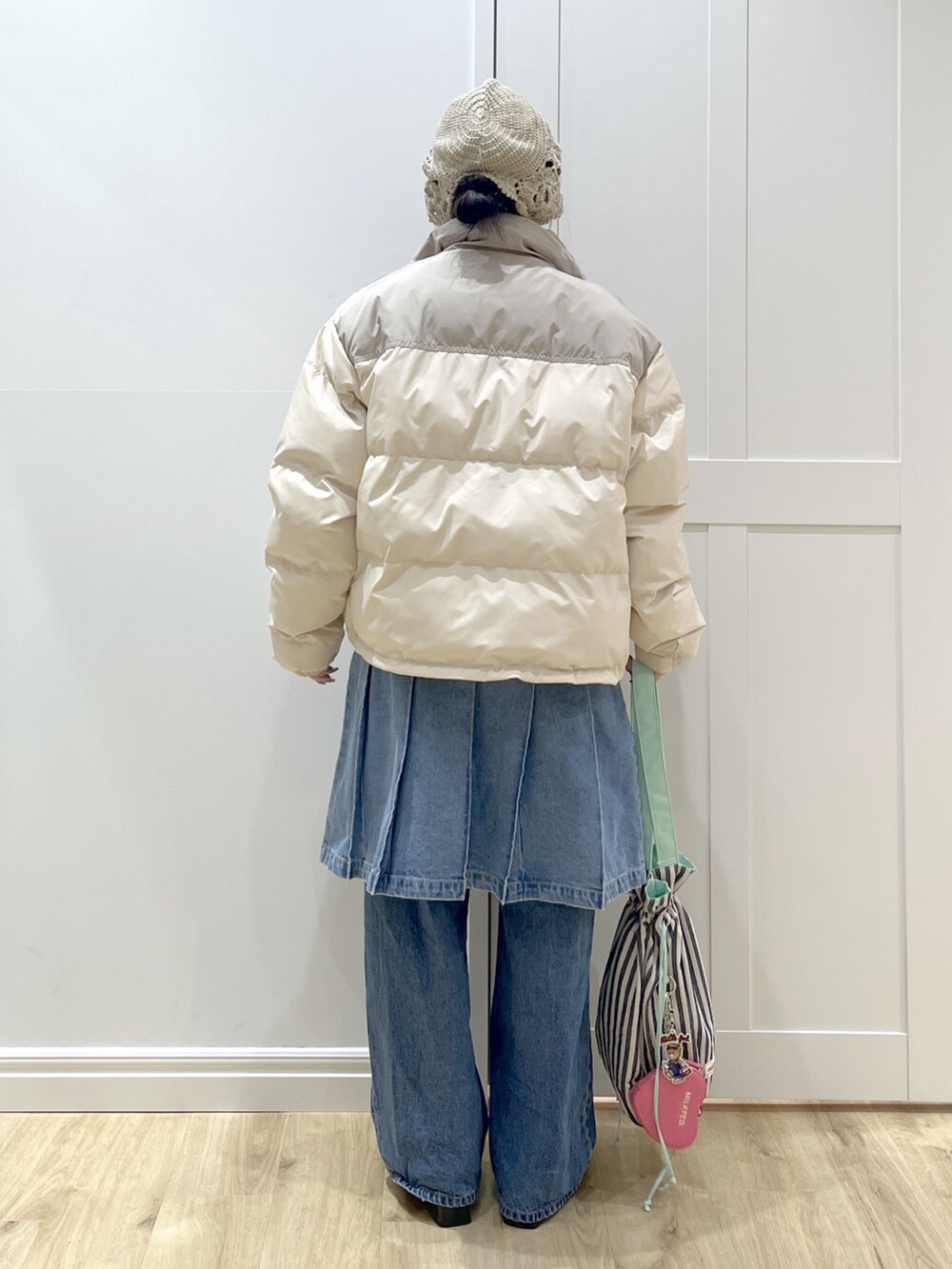 ホワイト系のダウンジャケット/コート、ベージュ系のTシャツ/カットソー、ブルー系のデニムパンツを着用したレディースの冬コーディネートの3枚目の写真